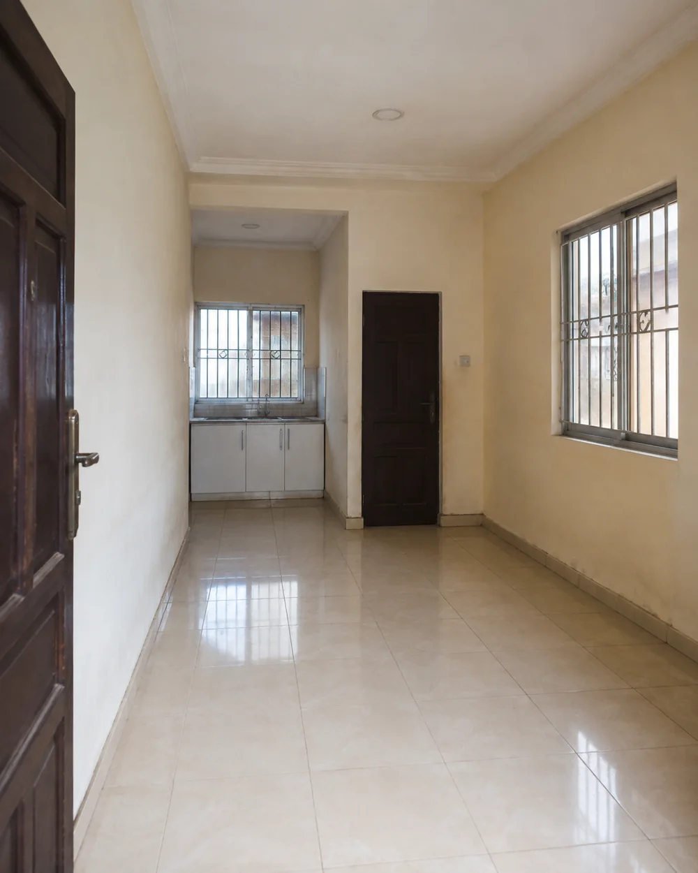 A vacant self-contained studio with a kitchenette and tiled floor